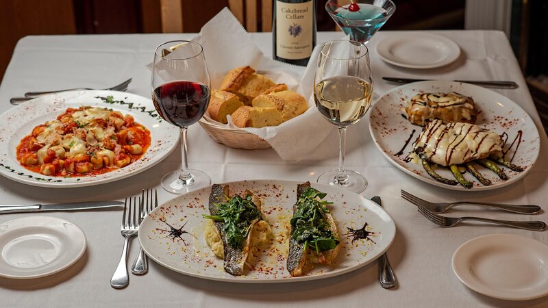 Multple plated entrees with focus on filet of fish entree topped with spinach